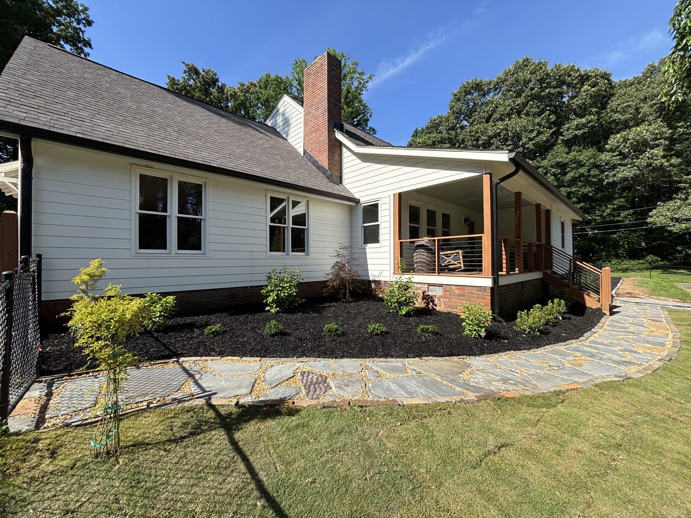 Curved flagstone walkway past a freshly mulched planting bed and new sod